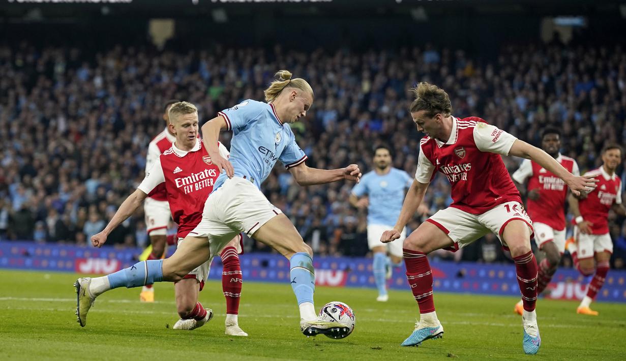 Pemain Manchester City, Erling Haaland, berusaha melewati pemain Arsenal pada laga Liga Inggris di Stadion Etihad, Kamis (27/4/2023). Arsenal takluk dengan skor telak 1-4. (AP Photo/Dave Thompson)