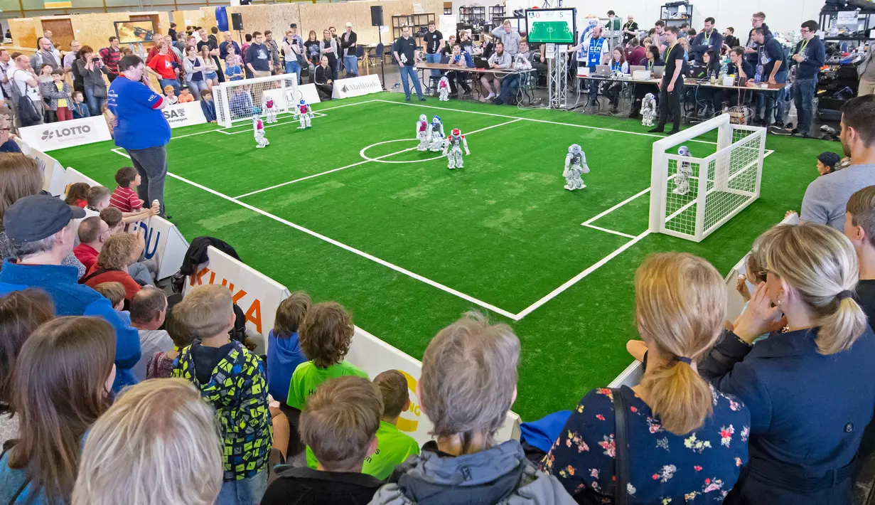 Sejumlah orang menonton pertandingan sepak bola antar tim robot 'Nomadz' dari Swiss melawan robot tim 'Hulk' dari Jerman dalam pertandingan Liga Platform Standar di RoboCup GermanOpen 2018, Magdeburg, Jerman (28/4). (AP/Jens Meyer)