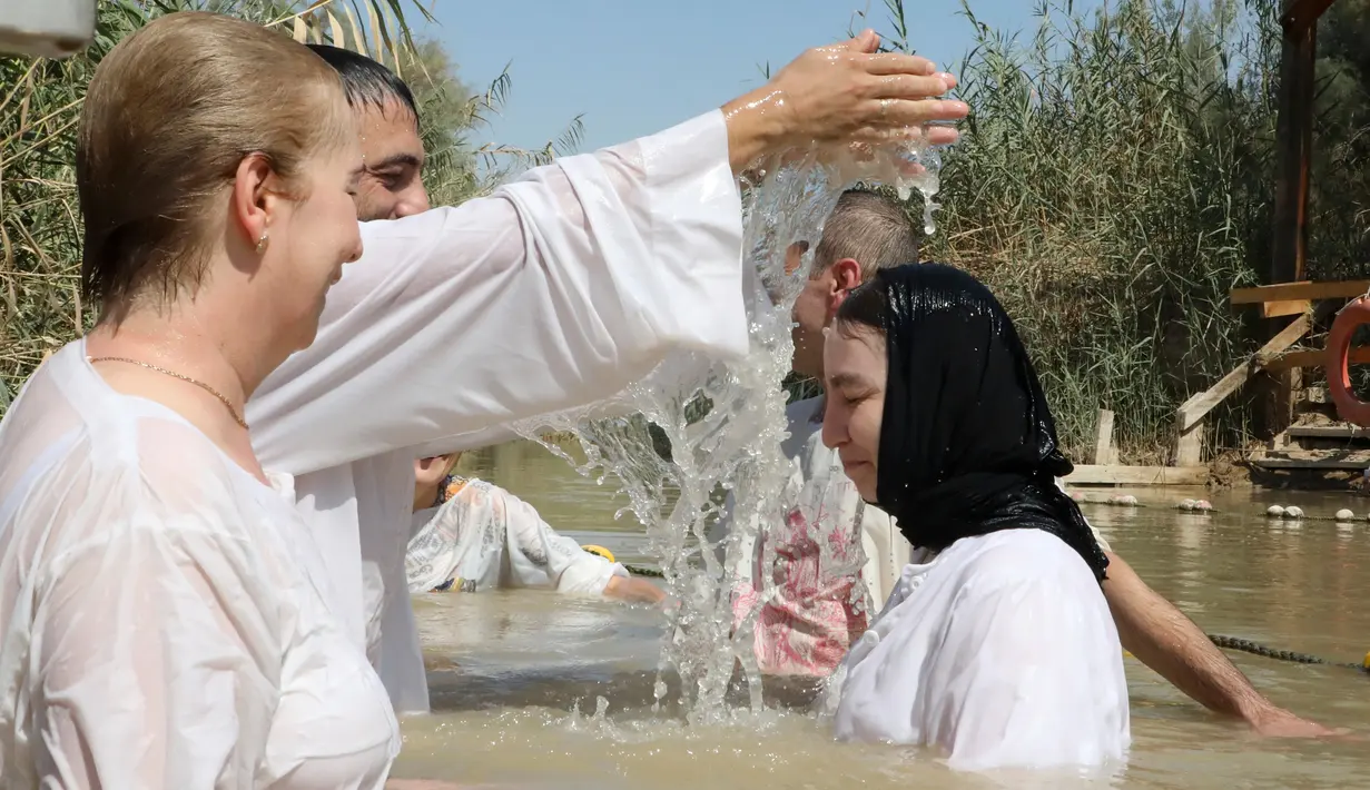 Pendeta membaptis umat Kristen di Sungai Yordan, Jericho, Palestina, Jumat (13/9/2019). Situs religi ini sejak tahun 1967 dikenal dengan nama dalam bahasa Arab Qasr al-Yahud. (HAZEM BADER/AFP)