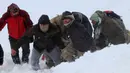 Tim penyelamat membawa korban salju longsor di Bahcesehir, Provinsi Van, Turki, Rabu (5/2/2020). Salju longsor kedua menghantam sewaktu 300 personel penyelamat mencari dua orang yang hilang dalam salju longsor sebelumnya. (Feyat Erdemir/DHA via AP)