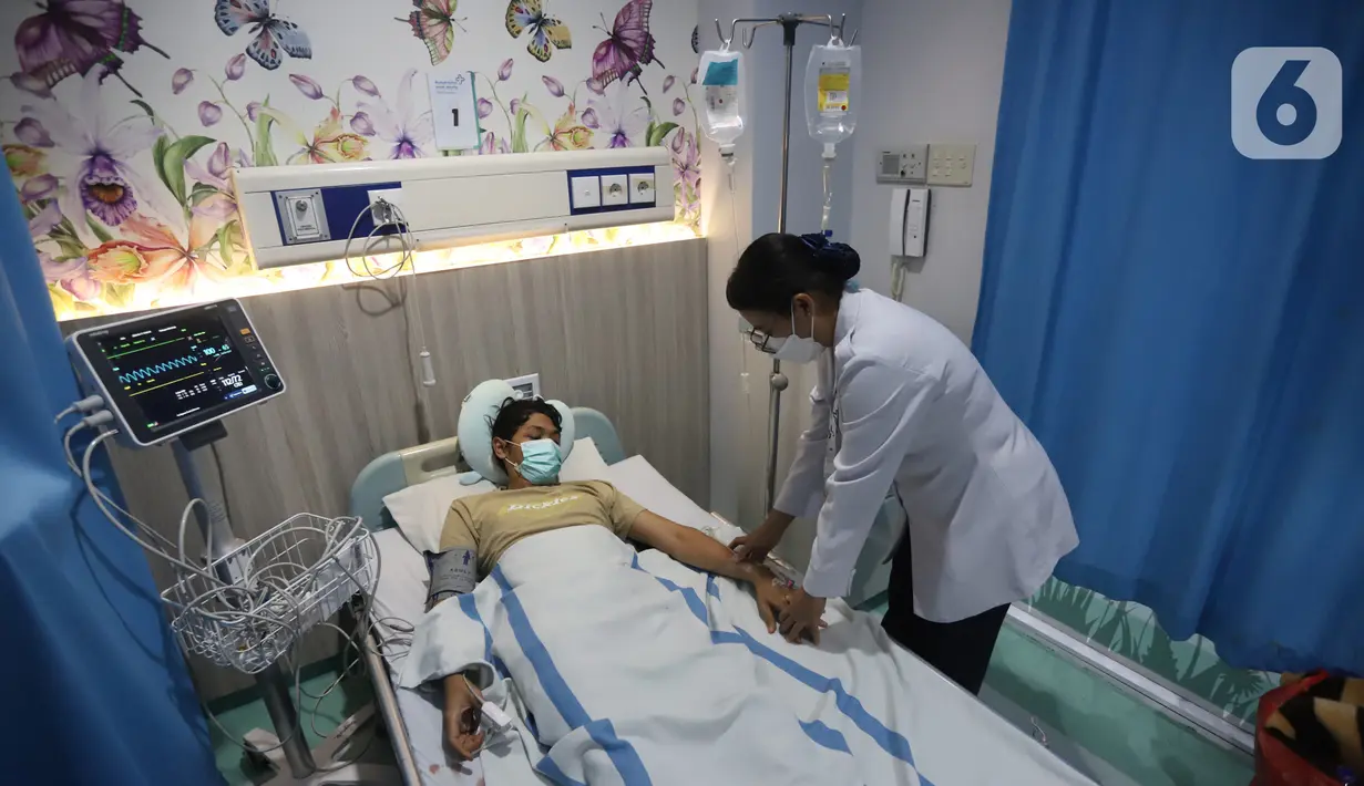 Tenaga kesehatan memeriksa kondisi salah satu pasien demam berdarah pada ruang perawatan pasien di RSUD Taman Sari, Jakarta Barat, Rabu (17/4/2024). (merdeka.com/Arie Basuki)
