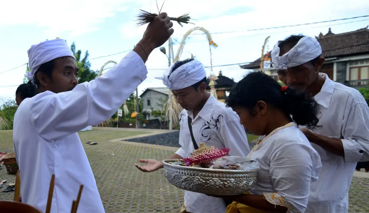 Seorang pemuka agama mencipratkan air suci pada beberapa warga Bali yang mendatangi pura di Jimbaran, Bali, Rabu (21/5/14). (AFP PHOTO/Sonny Tumbelaka)