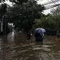 Warga melintasi banjir di Jalan Hang Lekir, Kebayoran Lama, Jakarta Selatan, Rabu (1/1/2020). Banjir tersebut disebabkan karena tingginya intensitas hujan yang mengguyur sejak Selasa (31/12/2019). (Liputan6.com/Johan Tallo)