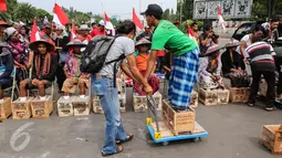 Seorang relawan membawa petani dengan menggunakan troli saat melakukan aksi protes pasung kaki dengan semen di depan Istana Merdeka, Kamis (16/3). Mereka berasal dari Pati, Kudus dan Karawang. (Liputan6.com/Fery Pradolo)