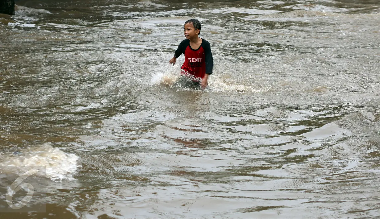 Seorang anak asyik bermain banjir yang merendam kawasan Benhil RT 03 RW 05, Jakarta Pusat, Selasa (21/1). Hujan deras yang mengguyur sejak Selasa dinihari mengakibatkan kawasan tersebut mengalami banjir. (Liputan6.com/Johan Tallo)