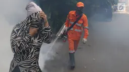 Seorang warga menutup wajah saat petugas melakukan pengasapan (fogging) di kawasan Kebon Baru, Tebet, Jakarta, Kamis (28/2). Pengasapan dilakukan terkait adanya warga di kawasan itu yang terkena penyakit demam berdarah. (Liputan6.com/Immanuel Antonius)