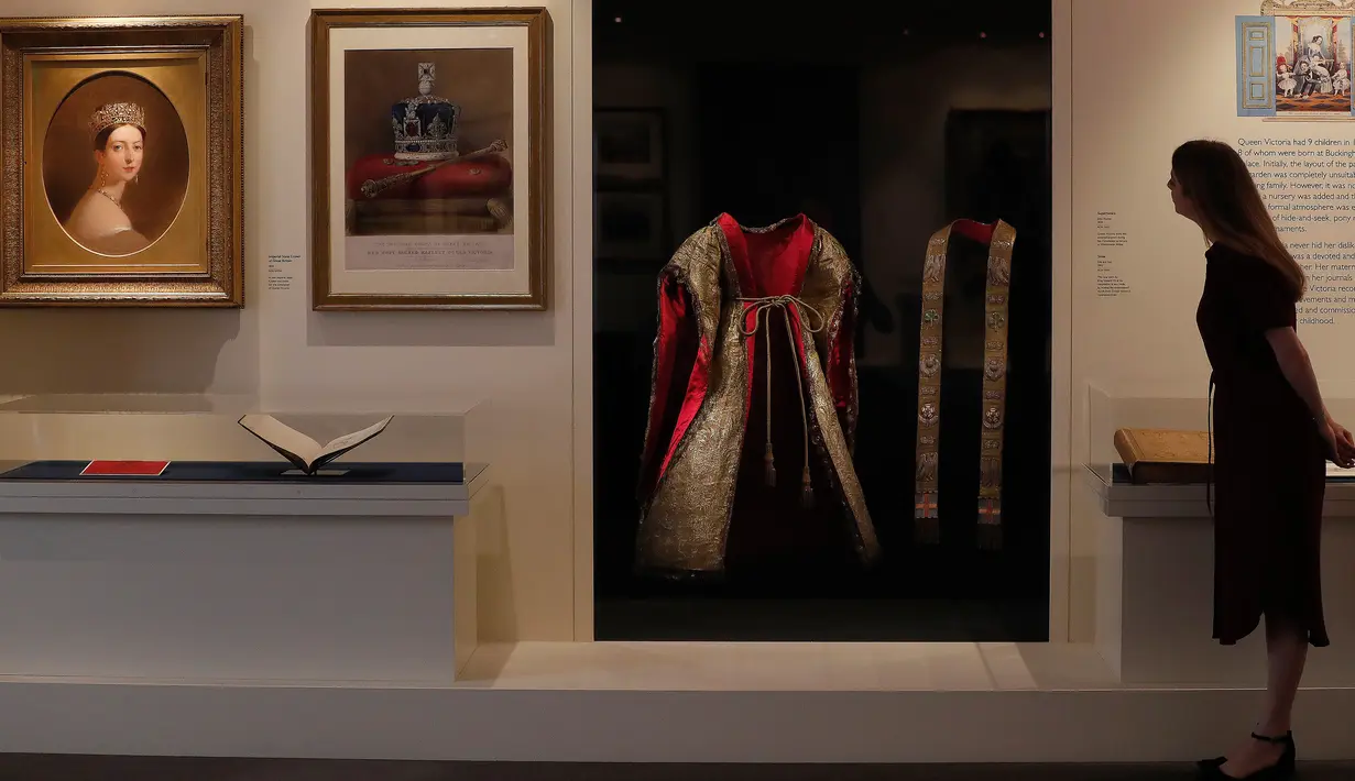 Seorang wanita melihat gaun upacara yang dikenakan Ratu Victoria pada upacara penobatannya tahun 1838 sebagai bagian dari pameran di Istana Buckingham, London, Rabu (17/7/2019). Pameran yang dibuka pada 20 Juli itu menandai peringatan 200 tahun kelahiran Ratu Victoria. (AP Photo/Frank Augstein)