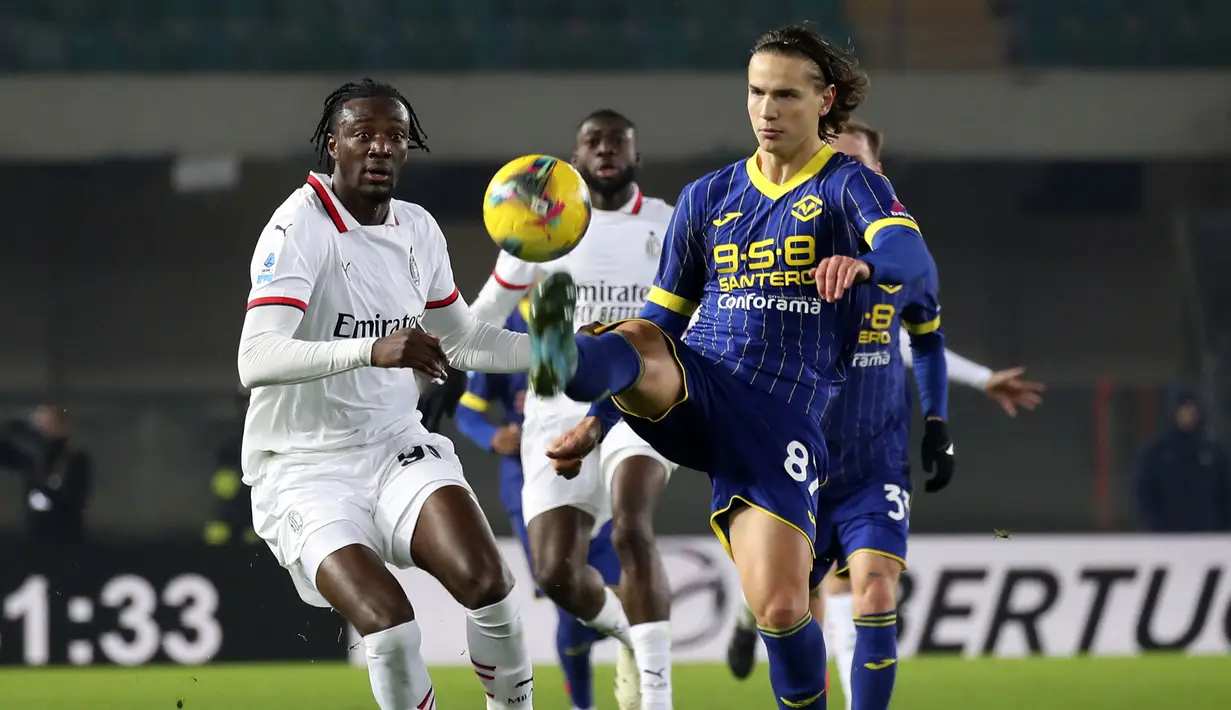 Pemain AC Milan, Tammy Abraham (kiri) berebut bola dengan pemain Hellas Verona, Daniele Ghilardi pada laga lanjutan Liga Italia 2024/2025 di Marcantonio Bentegodi, Verona, Italia, Sabtu (21/12/2024) dini hari WIB. (AP Photo/LaPresse/Paola Garbuio)