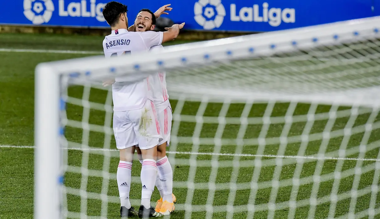 Gelandang Real Madrid, Eden Hazard berselebrasi dengan rekannya Marco Asensio usai mencetak gol ke gawang Deportivo Alaves pada pertandingan lanjutan La Liga Spanyol di stadion Mendizorroza di Vitoria, Minggu (24/1/2021). Madrid menang besar atas Alaves 4-1. (AP Photo/ Alvaro Barrientos)