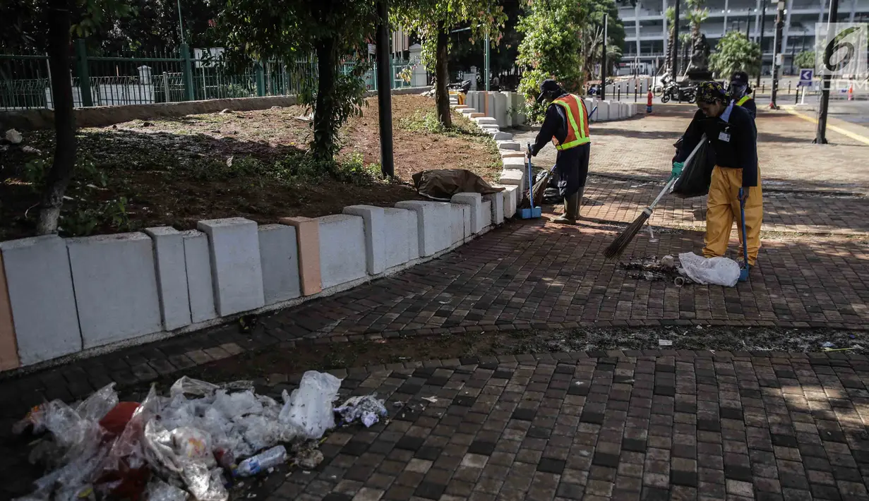 Petugas membersihkan sisa sampah bekas pertandingan Final Piala Presiden 2018 di area Stadion Utama Gelora Bung Karno, Jakarta, Senin (19/10). Sampah-sampah tersebut ditinggalkan para suporter Persija Jakarta dan Bali United. (Liputan6.com/Faizal Fanani)