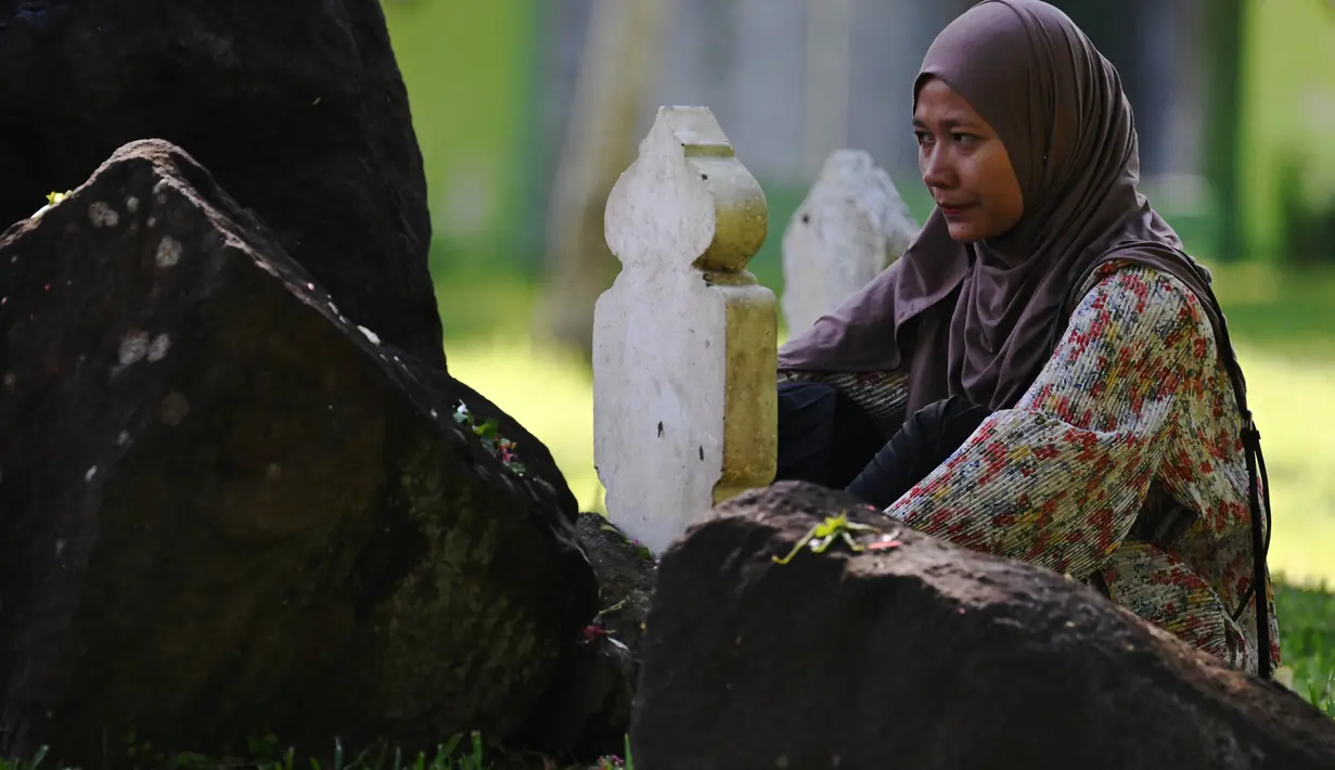 Seorang wanita berdoa untuk kerabat yang kehilangan nyawa dalam tsunami Samudra Hindia 2004 di sebuah kuburan massal di Banda Aceh pada 26 Desember 2024. (CHAIDEER MAHYUDDIN/AFP)