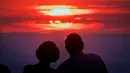 Pasangan melihat matahari terbenam di puncak gunung Feldberg dekat Frankfurt, Jerman,  (30/7). (AP Photo/Michael Probst)
