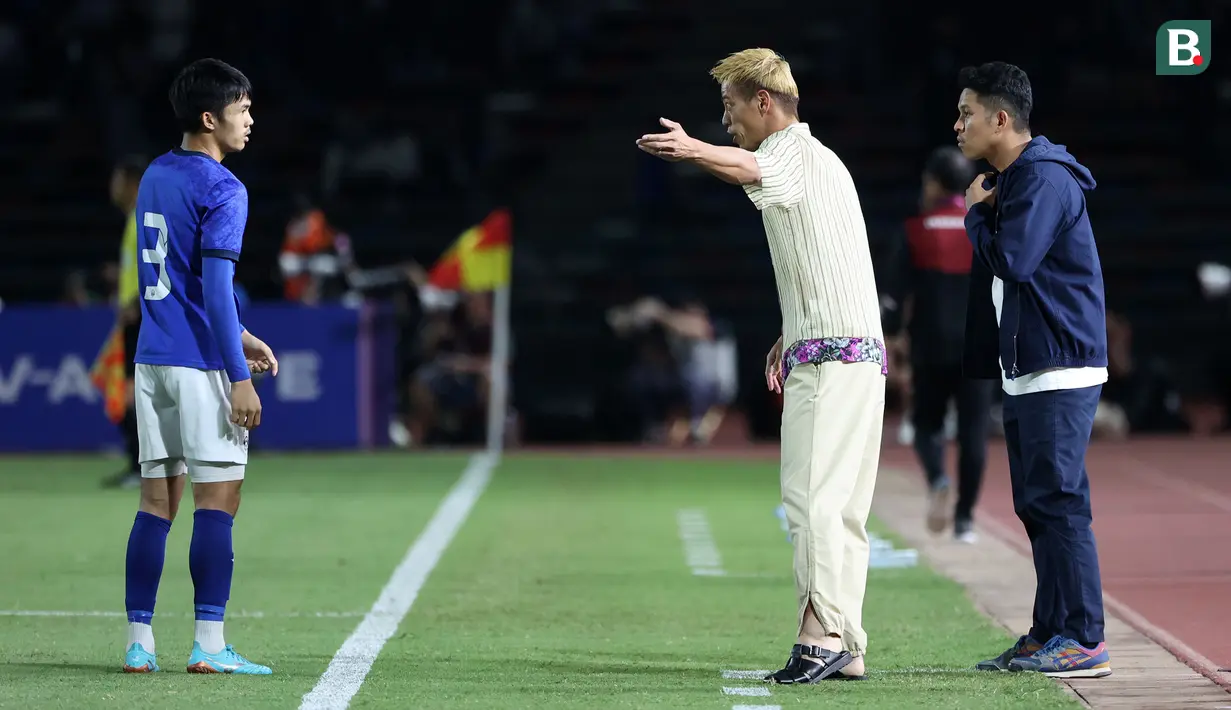 Pelatih Timnas Kamboja U-22, Keisuke Honda (kanan kedua) memberikan arahan kepada pemainnya saat laga Grup A Sepak Bola SEA Games 2023 melawan Timnas Indonesia di Olympic National Stadium, Phnom Penh, Kamboja, Rabu (10/5/2023) malam WIB. Honda terkenal dengan gaya berpakaian unik saat mendampingi Kamboja pada perhelatan akbar olahraga di Asia Tenggara tersebut. (Bola.com/Abdul Aziz)