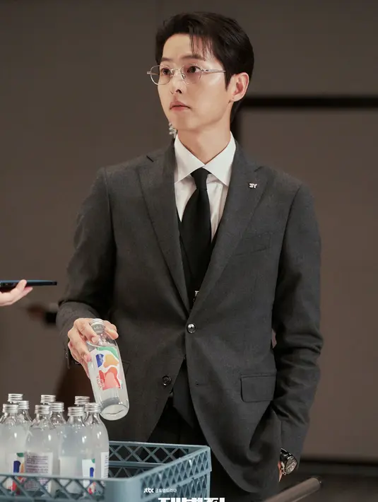 Mengenakan setelan jas rapi serta sepasang kacamata, Yoon Hyun Woo tampak tenang bahkan saat ia berurusan dengan pekerjaan yang sensitif dan berbahaya. (Foto: Soompi)