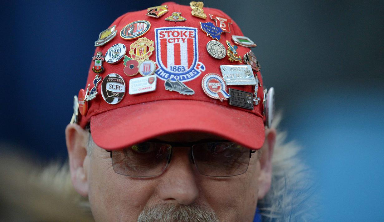 Seorang suporter Stoke City mengenakan topi dengan hiasan pin dari berbagai klub saat menonton timnya melawan Tottenham Hotspur pada lanjutan Liga Inggris di Stadion Britannia, Stoke, Selasa (19/4/2016) dini hari WIB. (AFP/Oli Scarff)