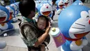 Seorang wanita saat menggendong anaknya untuk melihat patung karakter kartun terkenal Doraemon di Seoul, Korea Selatan,Senin (31/8/2015). Pameran ini menghadirkan seratus patung Doraemon  dengan berbagai pose yang berbeda. (REUTERS/Kim Hong – Ji)   