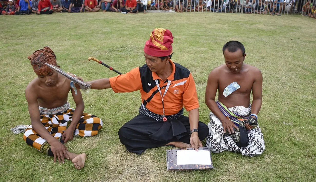 Seorang wasit (pekembar) memberikan hadiah kepada pepadu (petarung) dalam kesenian tradisional peresean di Praya, Lombok Tengah, Selasa (19/2). Selama pertarungan berlangsung, iringan musik gamelan Lombok tidak boleh berhenti. (MOH EL SASAKY/AFP)