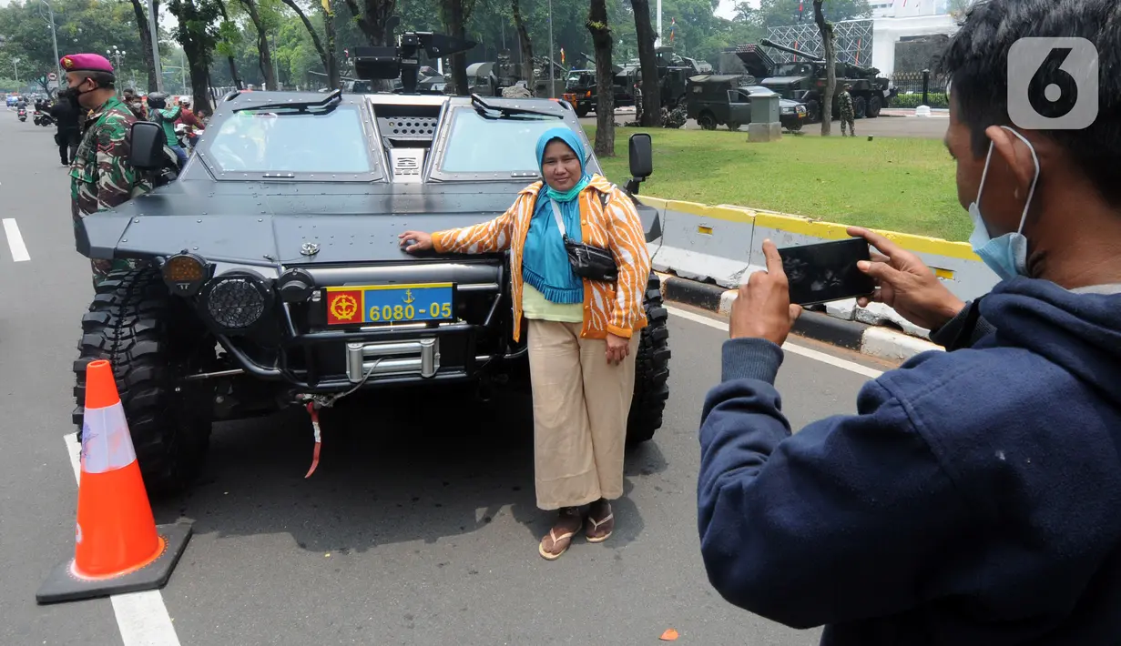 Warga berfoto dengan kendaraan taktis TNI yang dipamerkan di depan Istana Merdeka, Jakarta, Senin (4/10/2021). Ratusan alat utama sistem persenjataan (Alutsista) TNI dipamerkan sepanjang pinggir jalan sekeliling kawasan Monas dalam rangka peringatan HUT ke-76 TNI. ​(merdeka.com/Arie Basuki)