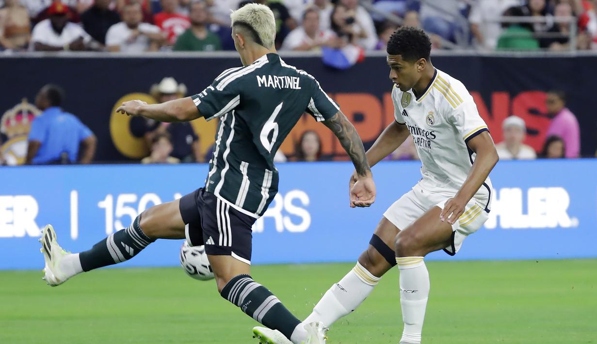Pemain Real Madrid, Jude Bellingham (kanan), menendang bola dan dihadang pemain MU, Lisandro Martinez (kiri), dalam pertandingan pramusim Soccer Champions Tour 2023 yang berlangsung di NRG Stadium, Houston, Kamis (27/7/23). Kedua pemain tersebut terlibat keributan di menit ke-42 setelah Martinez melakukan pelanggaran keras berupa tekel dengan kedua kakinya terhadap Jude Bellingham. (AP Photo/Michael Wyke)