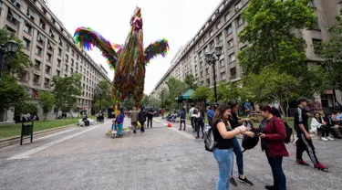 Orang-orang berjalan dekat seni instalasi "Hecho en Casa" berbentuk ayam jantan raksasa di Santiago, Chile, Senin (29/10). Ayam jantan setinggi empat meter itu dibuat oleh seniman China, Simone Chua dan Renzo Barriga dari Peru. (Martin BERNETTI/AFP)
