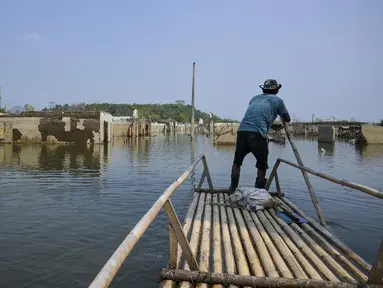 Seorang pria mengendalikan rakit bambunya di kawasan Bendungan Karian yang mengering di Kampung Somang, Lebak, Banten, Kamis (30/7/2026). (AFP/ Bay Ismoyo)