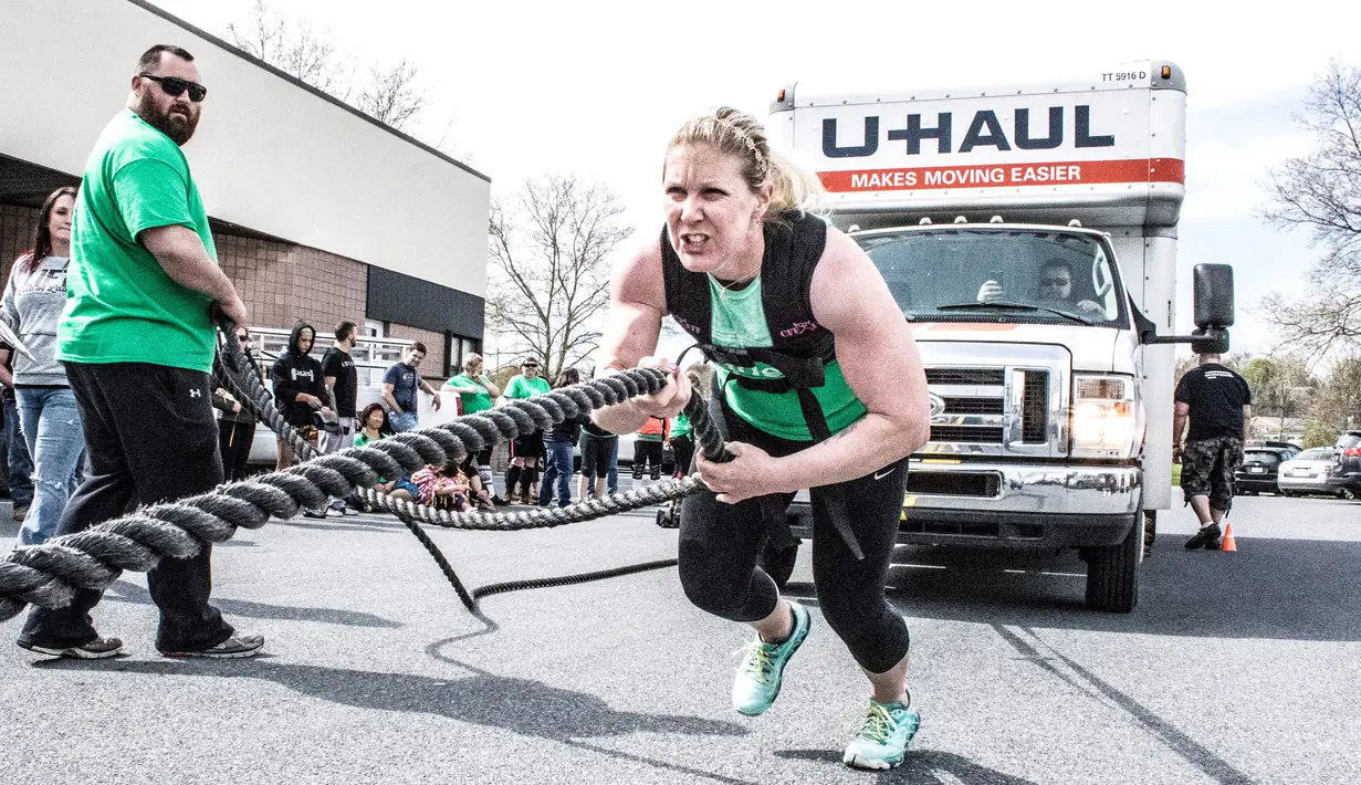 Seorang wanita menarik truk dengan tubuhnya saat kompetisi May Queen Spring Strongwoman di Lancaster, Pennsylvania, AS (25/4). Kegiatan tersebut untuk memperingati Hari Ibu. (Reuters)