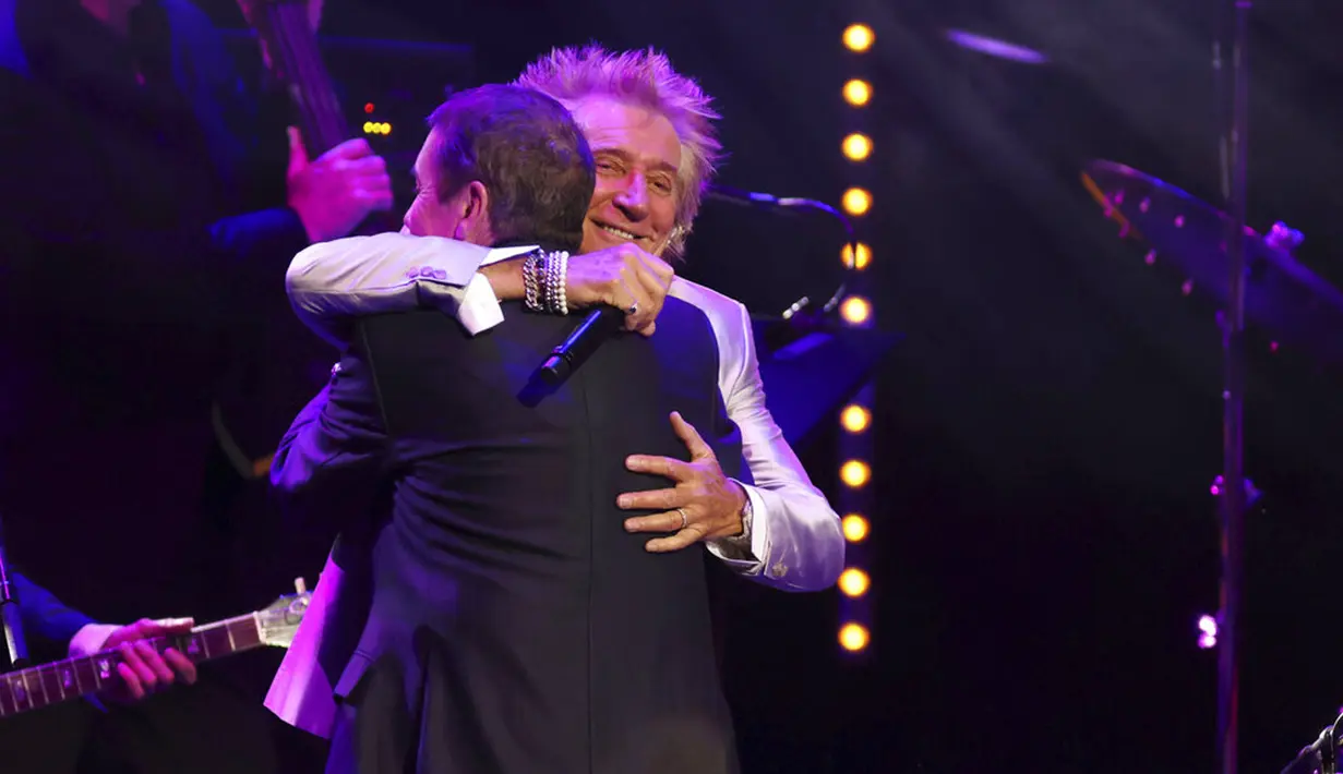 Rod Stewart merangkul Jools Holland pada konser amal untuk membantu kanker prostat Raise the Roof yang diselenggarakan oleh Jools Holland di Royal Albert Hall, London, Inggris, 22 Juni 2022. Rod Stewart sendiri sebelumnya berjuang melawan penyakit kanker prostat, namun kini telah mengalami remisi. (Suzan Moore/PA via AP)