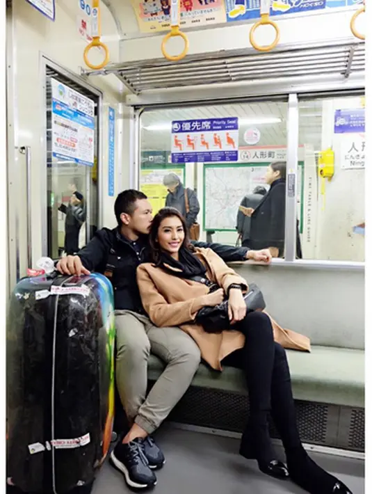 Keceriaan terlihat Tyas didalam kereta duduk bersender pada Raiden. Disebelahnya koper besar hitam barang bawaannya. (Instagram/@Tyasmirasih)