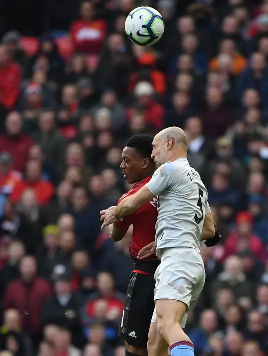 Penyerang Manchester United, Anthony Martial berebut bola udara dengan bek West Ham United, Pablo Zabaleta selama pertandingan lanjutan Liga Inggris di Old Trafford (13/4). MU menang tipis atas West Ham 2-1. (AFP Photo/Paul Ellis)