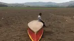 Seorang anak laki-laki duduk di atas kapal di Danau Atescatempa yang telah mengering, Guatemala, Jumat (5/5). Keringnya Danau Atescatempa disebabkan oleh dampak perubahan iklim di Amerika Tengah yang disebut "Koridor Kering". (AFP PHOTO / Marvin RECINOS)