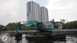 Petugas mengoperasikan eskavator untuk mengeruk lumpur di Kali Sunter Podomoro, Jakarta, Jumat (4/12). Pemprov DKI bersama Kementrian PU melakukan pembebasan bantaran sungai. (Liputan6.com/Gempur M Surya)