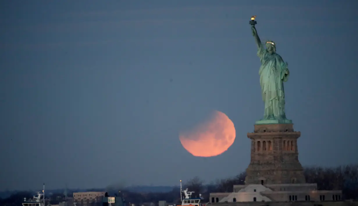 Pemandangan ketika Patung Liberty dihiasi oleh supermoon di Brooklyn, New York, Amerika Serikat, Rabu (31/1). Supermoon membuat purnama dan gerhana tampak lebih besar dari biasanya. (AP Photo/Julio Cortez)