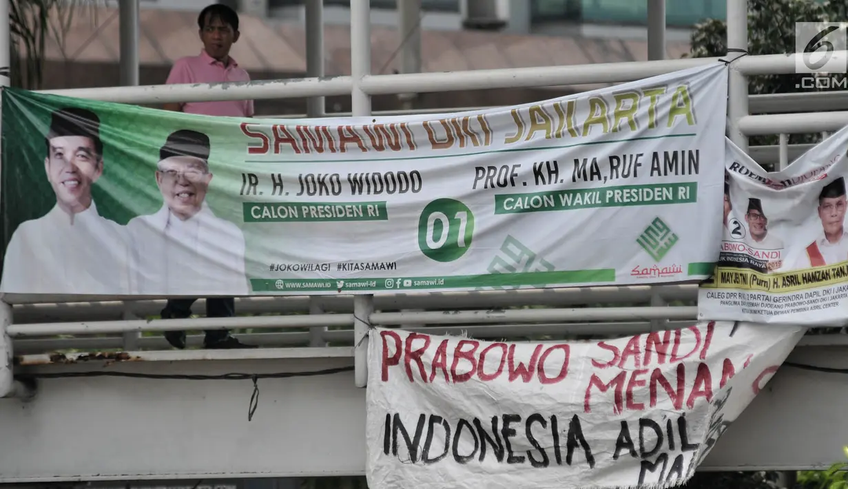 Warga melintas di dekat Spanduk Rakyat dukungan Prabowo-Sandiaga yang terpasang di JPO Jakarta, Selasa (9/4). Berbeda dengan spanduk pada umumnya, Spanduk Rakyat merupakan karung bekas yang dibuat oleh pendukung Prabowo-Sandiaga yang ditulis dengan cat atau spidol. (merdeka.com/Iqbal S. Nugroho)