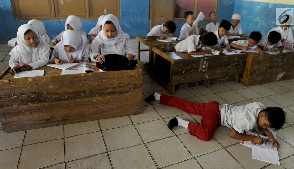 Murid-murid kelas V melakukan kegiatan belajar pada meja yang diubah menjadi kursi dan tempat belajar di SDN Kertajaya 2, Rumpin, Bogor (22/7/2019). Sudah lebih dari tiga tahun mereka belajar  pada fasilitas yang minim. (merdeka.com/Arie Basuki)