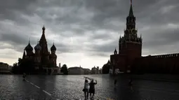 Orang-orang menutupi diri mereka dengan kantong plastik saat hujan di Lapangan Merah di Moskow, Rusia, 7 Juli 2020. Cuaca panas di Moskow terus berlanjut, dengan suhu diperkirakan mencapai lebih dari 30 derajat Celcius. (AP Photo/Pavel Golovkin)
