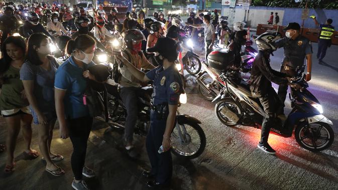 Polisi memeriksa suhu tubuh warga di pos pemeriksaan virus corona COVID-19 di Manila, Filipina, Senin (16/3/2020). Polisi beserta petugas lalu lintas dan petugas desa melakukan pengecekan suhu tubuh warga untuk mencegah penyebaran virus corona COVID-19. (AP Photo/Aaron Favila)