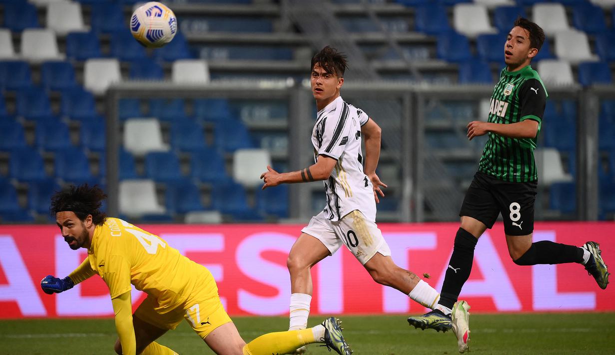 Striker Juventus, Paulo Dybala (tengah) melepaskan tendangan yang berbuah gol ketiga timnya ke gawang Sassuolo dalam laga lanjutan Liga Italia 2020/2021 pekan ke-36 di Mapei-Citta del Tricolore Stadium, Rabu (12/5/2021). Juventus menang 3-1 atas Sassuolo. (AFP/Marco Bertorello)