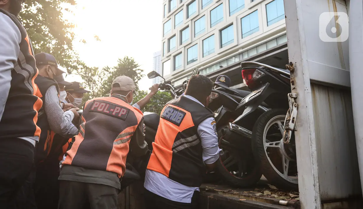 Petugas gabungan yang terdiri dari Satpol PP dan Dinas Perhubungan (Dishub) DKI Jakarta mengangkut motor yang terjaring razia ke atas truk di lokasi Citayam Fashion Week, kawasan Stasiun Dukuh Atas, Sudirman, Selasa (26/7/2022). Dishub DKI Jakarta mengamankan sebanyak 16 sepeda motor yang terpakir secara liar. (Liputan6.com/Faizal Fanani)