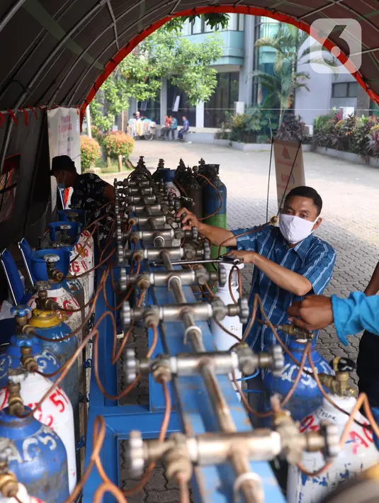 Petugas mengisi tabung oksigen di halaman gedung MUI Kota Tangerang, Banten, Kamis (15/7/2021). Kegiatan tersebut guna memudahkan warga Kota Tangerang dalam mengisi Oxygen Medis yang di masa PPKM Darurat yang kini sulit untuk mencari tempat pengisian tersebut. (Liputan6.com/Angga Yuniar)