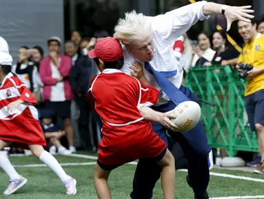 Walikota London Boris Johnson (kanan) bertabrakan dengan seorang anak selama bermain Rugby, Tokyo, Jepang, Kamis (15/10/2015).  Boris bermain Rugby untuk menyambut Jepang sebagai tuan rumah Piala Dunia Rugby 2019. (REUTERS/Issei Kato) 