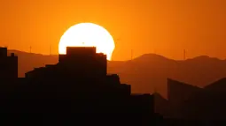 Gerhana matahari sebagian saat terbenam di cakrawala di Beijing, Kamis (10/6/2021). Uniknya fenomena gerhana matahari cincin ini yakni terjadi 18 bulan sekali. Adapun momen terlihatnya gerhana matahari cincin hanya 3 menit saja.  (AP Photo/Ng Han Guan)