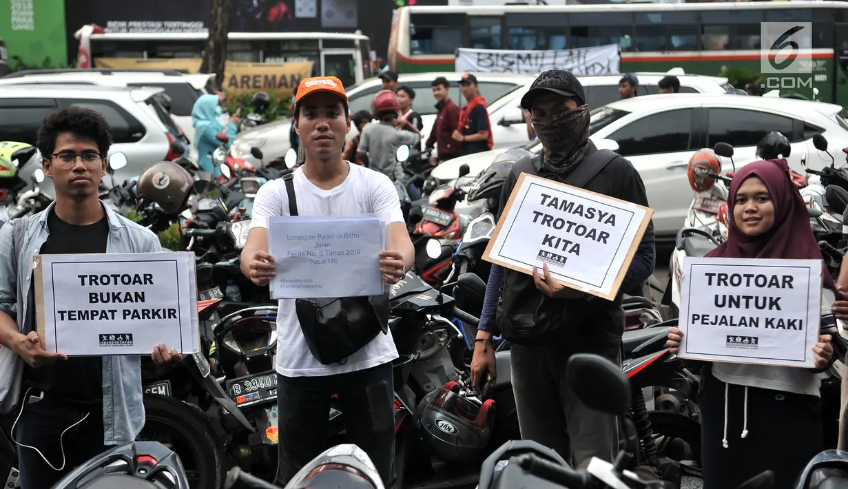 Anggota Koalisi Pejalan kaki menyelipkan selebaran di salah satu sepeda motor yang parkir di trotoar depan GBK, Jakarta, Minggu (9/12). Aksi tersebut dalam rangka menyadarkan masyarakat tentang pelanggaran parkir liar. (Merdeka.com/Iqbal S. Nugroho)