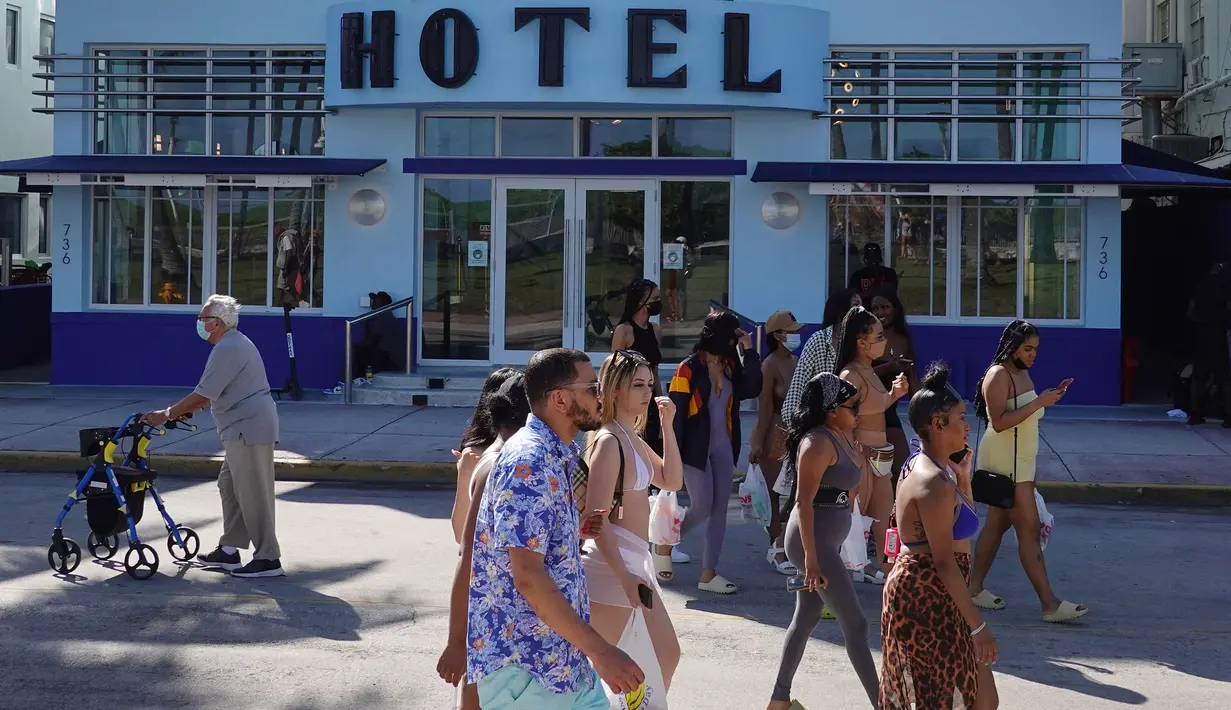 Orang-orang berjalan di sepanjang Ocean Drive di Miami Beach, Florida, Selasa (16/3/2021). Mahasiswa telah tiba di daerah Florida Selatan untuk liburan musim semi. Para pejabat kota prihatin dengan kerumunan liburan musim semi saat pandemi COVID-19 terus berlanjut. (Joe Raedle/Getty Images/AFP)