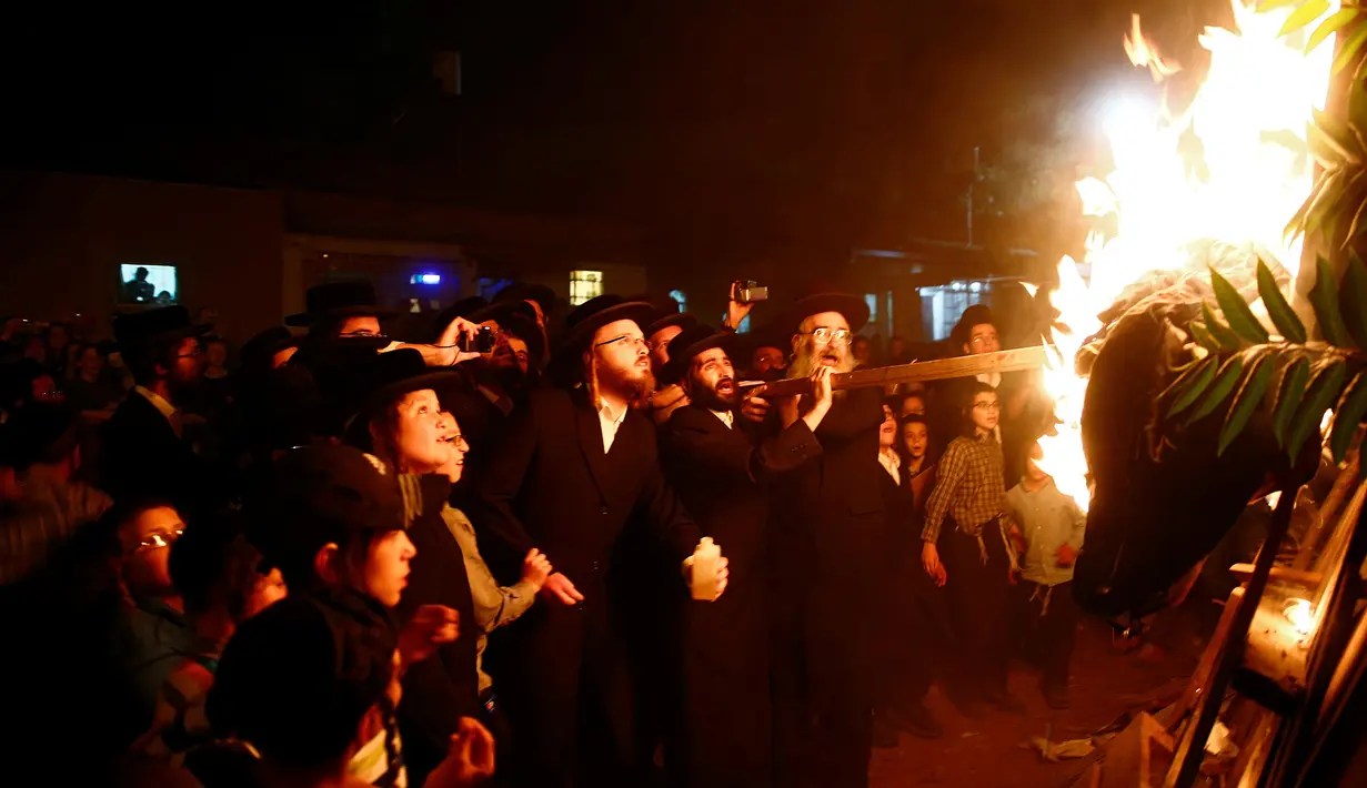 Sejumlah warga Yahudi Ultra-Ortodoks menambahkan kayu bakar pada api unggun selama perayaan hari libur Yahudi Lag Ba-Omer di Shearim, Yerusalem, (25/5). Hari libur Yahudi ini terjadi pada hari ke-18 dari bulan Ibrani dari Iyar. (REUTERS/Ronen Zvulun)