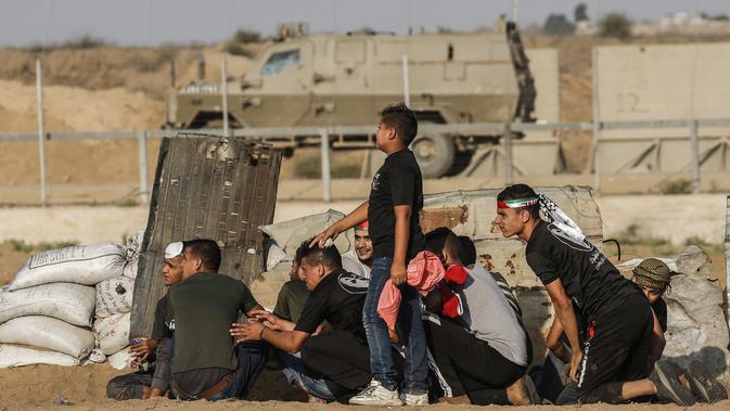 Warga Palestina berlindung dari pasukan Israel saat bentrok di Khan Yunis, Jalur Gaza, Jumat (13/9/2019). Kementerian Kesehatan Palestina mengatakan 55 warganya terluka oleh peluru tajam dan bom gas air mata pasukan Israel. (SAID KHATIB/AFP)
