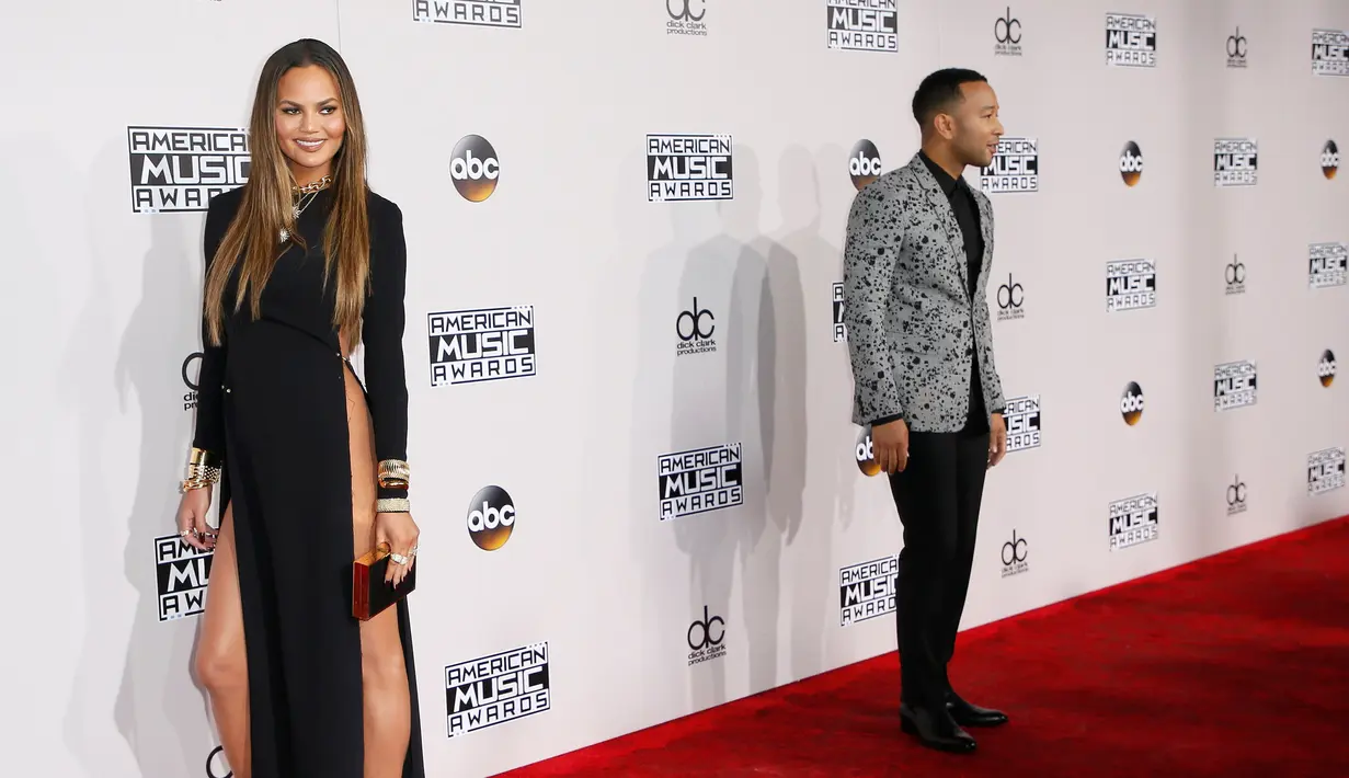 Model Chrissy Teigan dan John Legend berpose di karpet merah American Music Awards (AMA) 2016 di Los Angeles, California, Minggu (20/11). Gaun hitam berisiko itu membuat Chrissy menarik perhatian saat berpose di karpet merah. (REUTERS/Danny Moloshok)