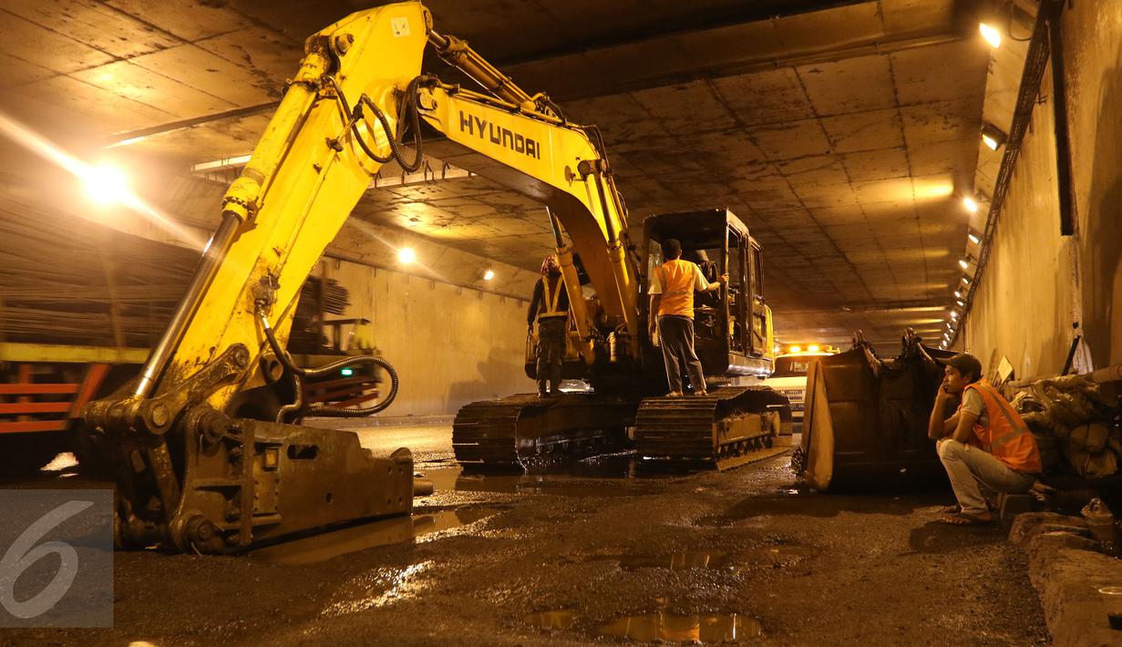 Pekerja menggunakan alat berat untuk memperbaiki jalan yang rusak berlubang di ruas Tol JORR tepatnya di terowongan Pasar Rebo, Jakarta, Senin (29/2) malam. Kondisi jalan yang rusak itu menyebabkan kemacetan panjang. (Liputan6.com/Herman Zakharia)