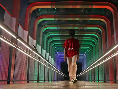 Warga melintasi jembatan penyebrangan orang (JPO) Polda Metro Jaya yang berhias lampu berwarna bendera Palestina, Jakarta, Rabu (19/5/2021). Pemprov DKI Jakarta melakukan aksi solidaritas untuk Palestina dengan menampilkan warna-warna khas bendera Palestina di 10 JPO. (Liputan6.com/Herman Zakharia)