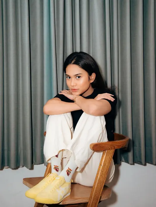 Gaya simple sporty ala Azizah Salsha pakai kaus hitam dan celana panjang putih, kaus kaki putih dengan corak, dan sepatu kuning. [Foto: Instagram/azizahsalsha_]