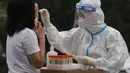 <p>Seorang pekerja medis mengambil sampel swab dari seorang warga selama pengujian massal untuk COVID-19 di distrik Chaoyang, Bejing, Senin (25/4/2022). Ibu kota China, Beijing, mulai menguji jutaan penduduk dan menutup kawasan perumahan dan bisnis pada Senin di tengah wabah baru COVID-19. (AP Photo/Ng Han Guan)</p>